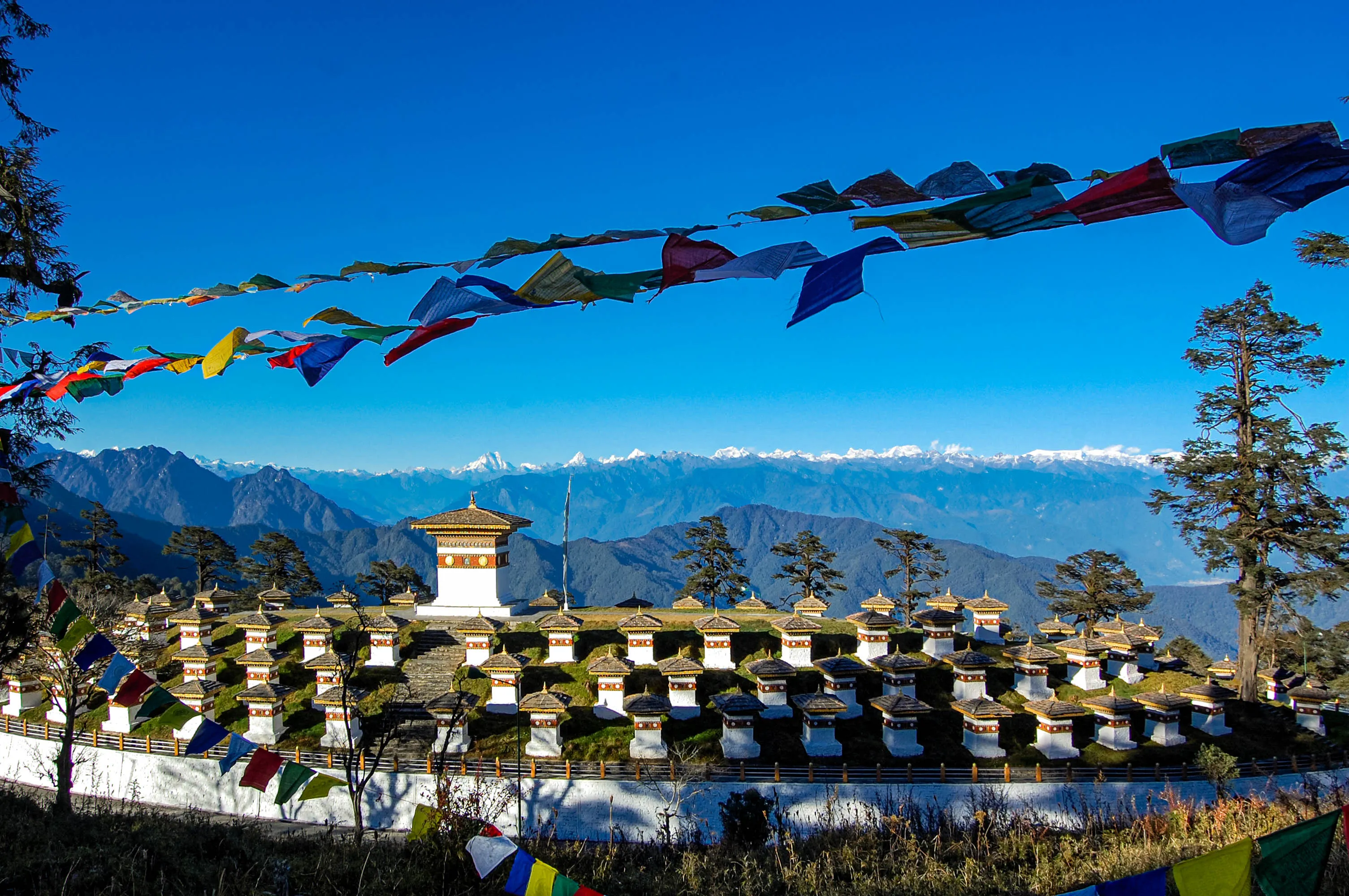 The Druk Wangyal Chortens standing in tiers on the crest of Dochula, prayer flags strung above them