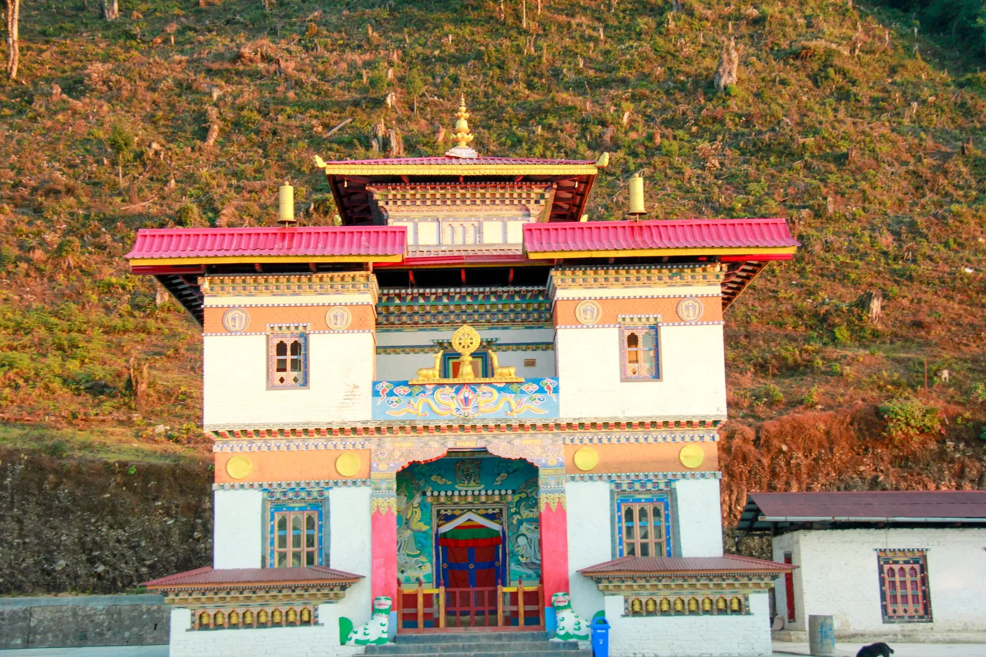 The front of the temple at Jashar Goenpa: a Dharma wheel flanked by two deer above the painted doorway, with snow-lion statues at the steps