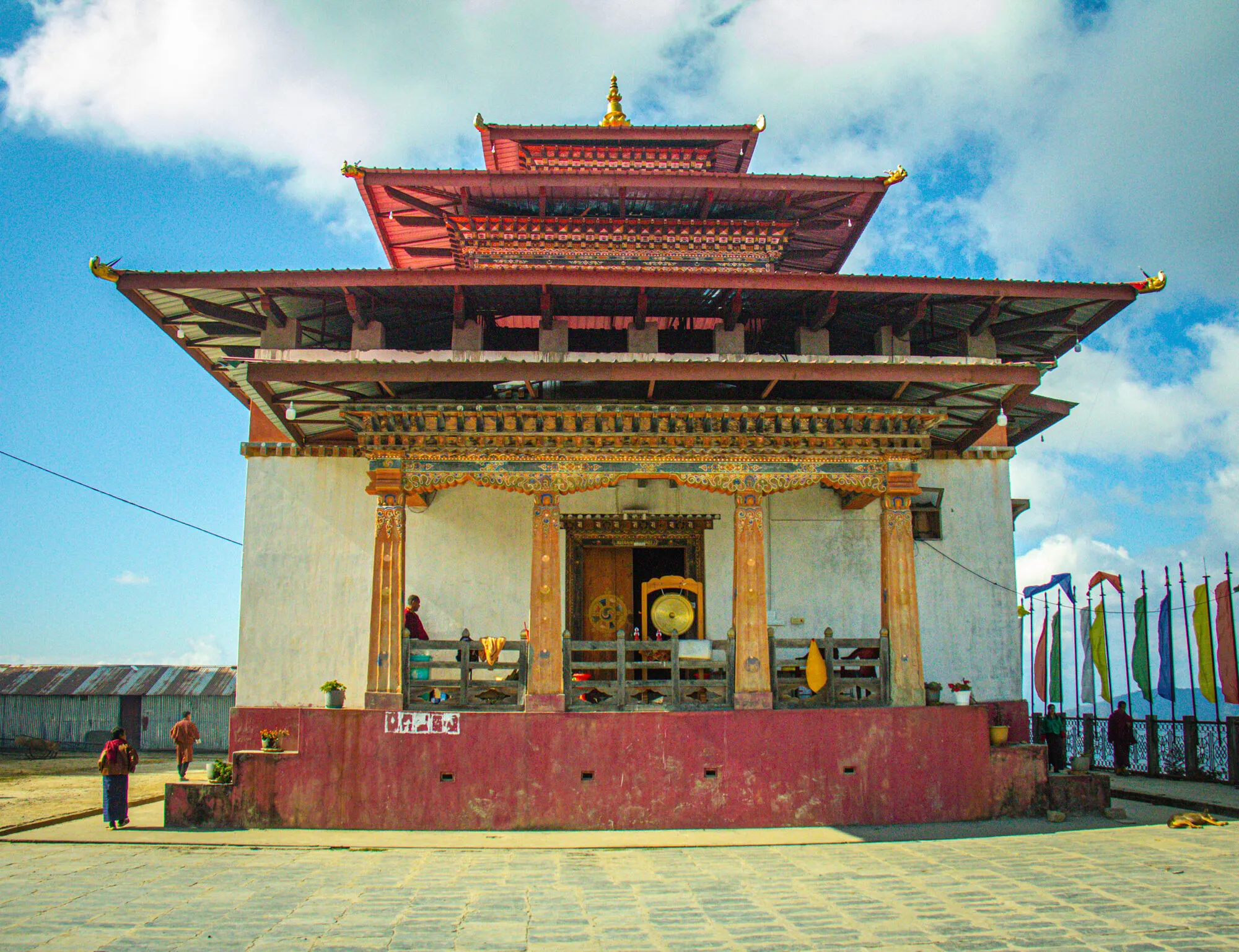 Khahor Goenpa’s main lhakhang face-on across its stone courtyard, a gong and a prayer drum on the porch and prayer flags to the right
