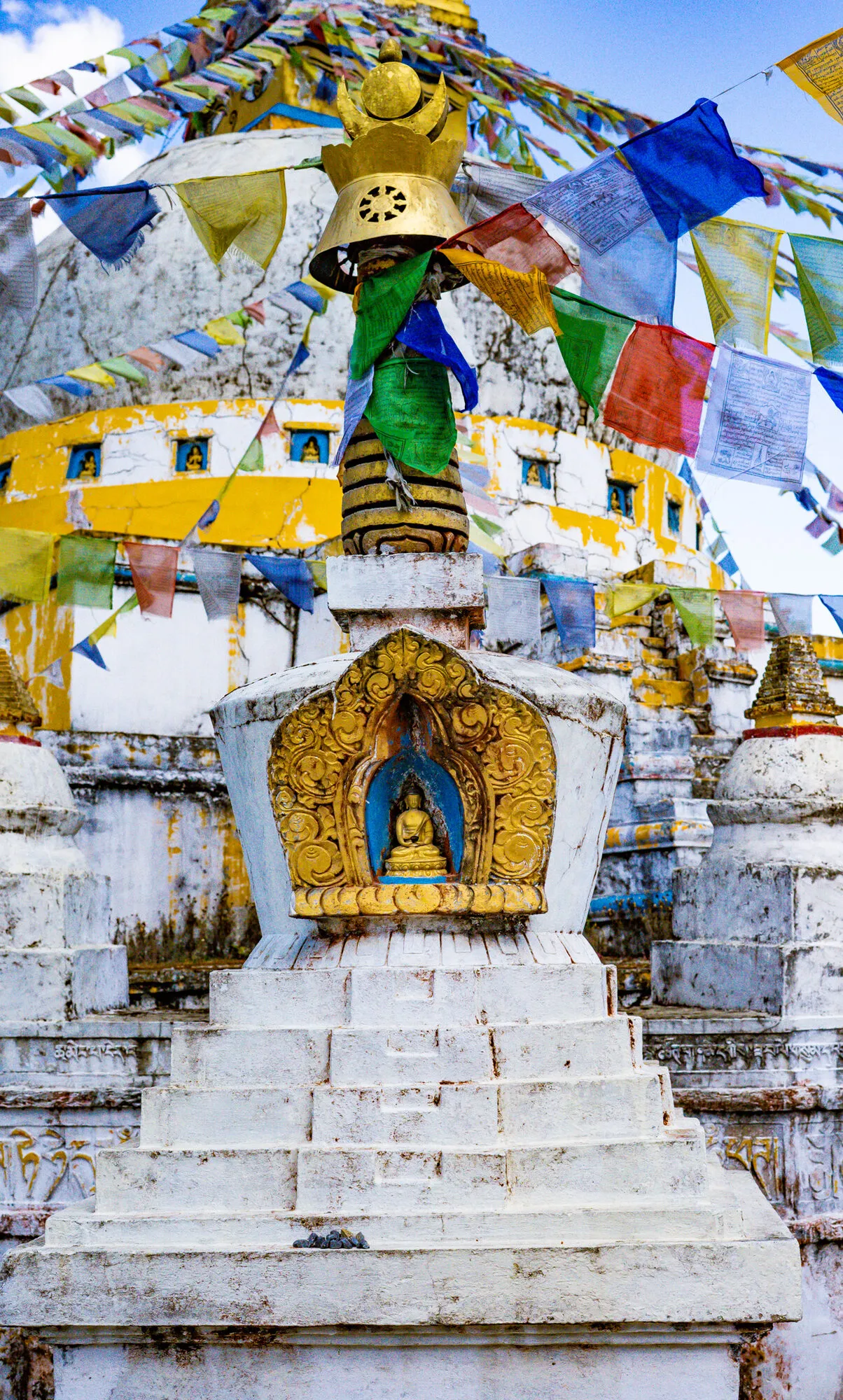 One of the small niche chortens in the ring around the Tsebar chorten, the big stupa’s dome and prayer flags behind